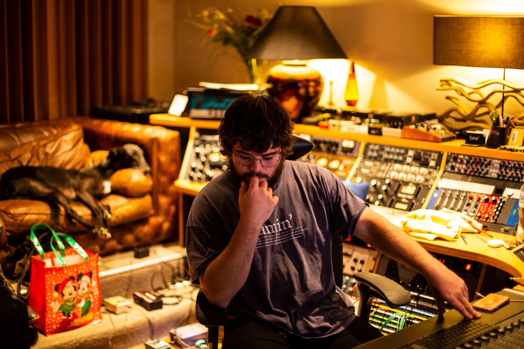 An engineer at the console, the studio dog asleep on the chesterfield behind